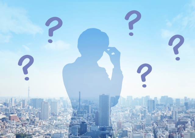 都会の背景で考えるシルエットの男性
