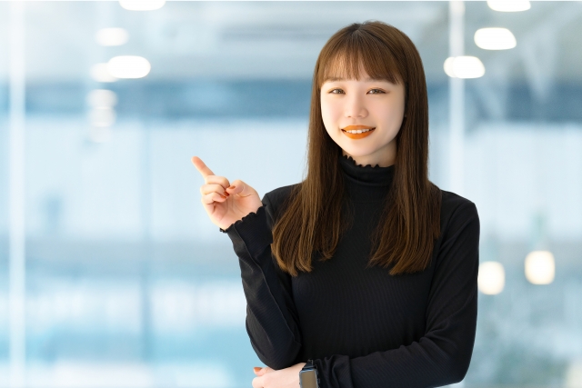 ガラス越しに指をさす笑顔の女性